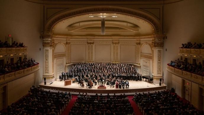 卡内基音乐厅俯视图，座无虚席的观众和合唱团和管弦乐队挤满了舞台