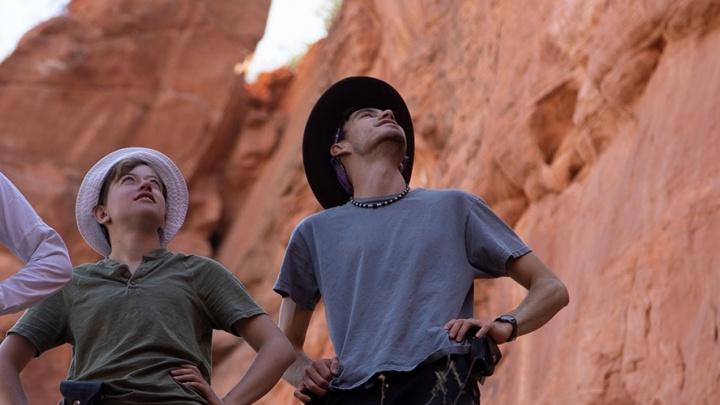 two students and their professor look up into a canyon