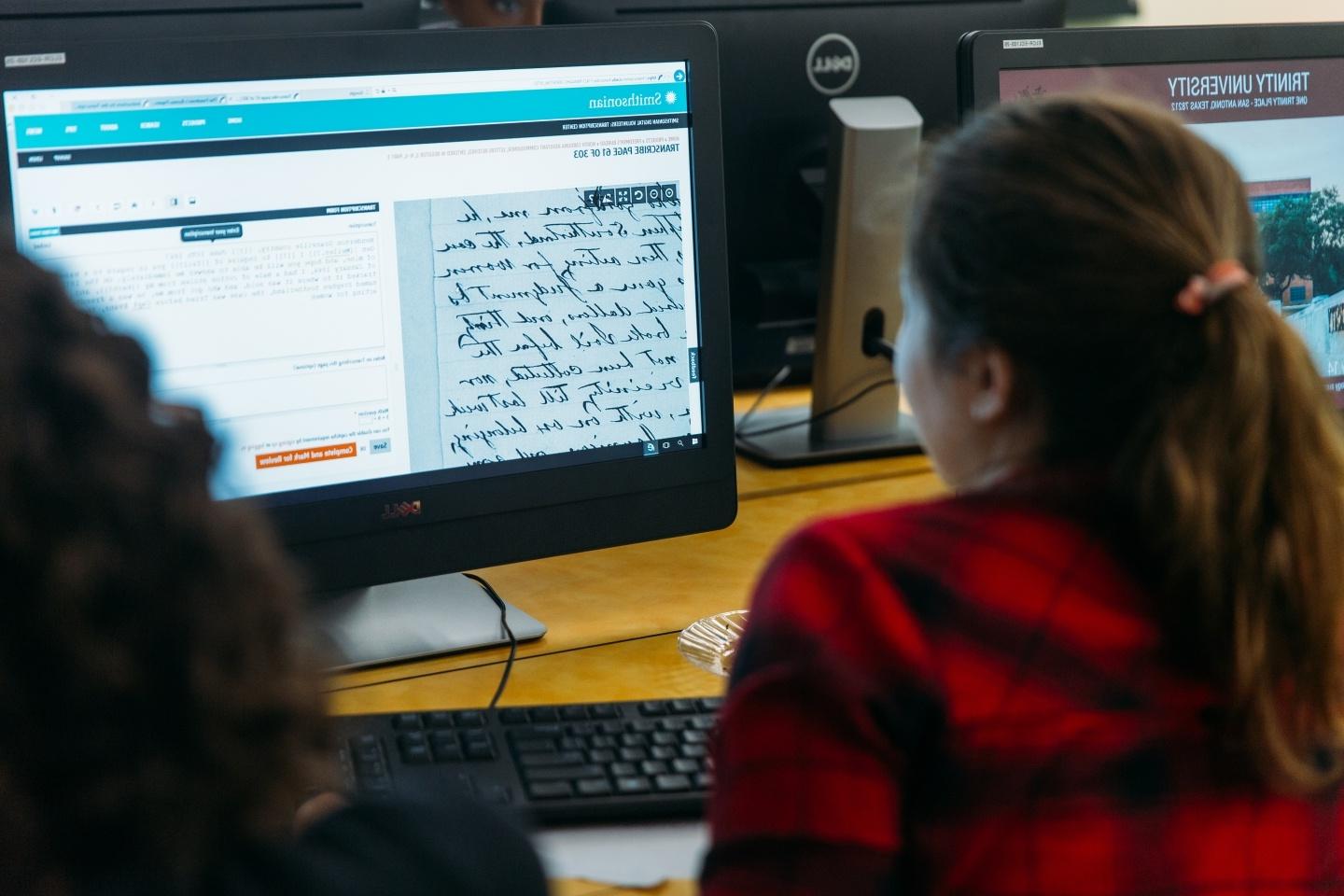 Student looking at computer screen comparing digital version of ancient manuscript and translation next to it