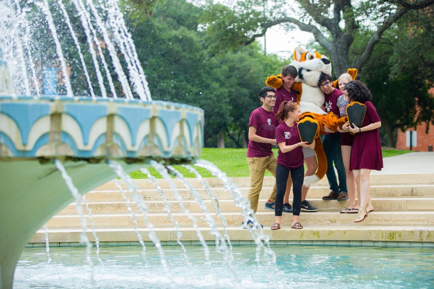 a group of students walks down the steps to dunk LeeRoy the Tiger in Miller Fountain