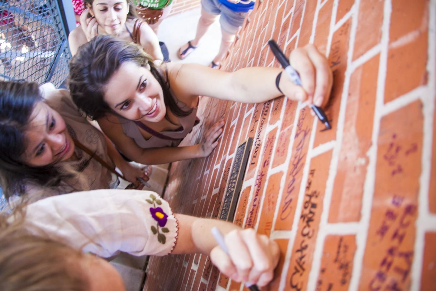 three women students sign bricks inside Murchison Tower