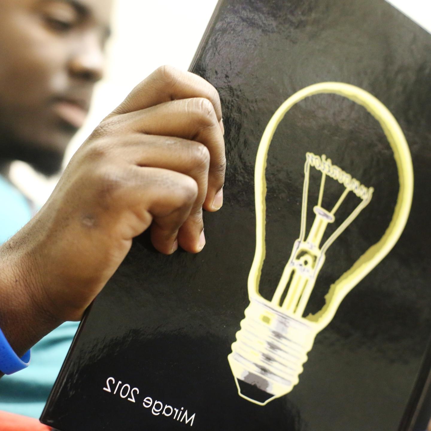 一名学生正在阅读2012年版的幻影，封面上有一个灯泡