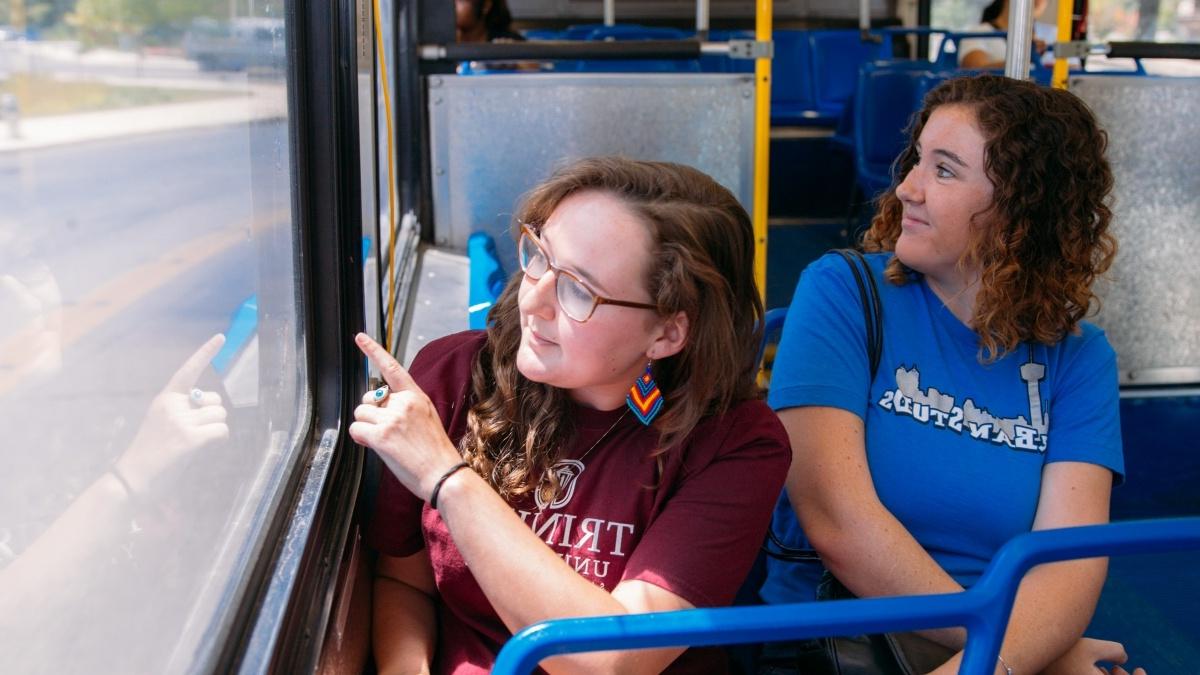 Two students riding a city bus looking out the window