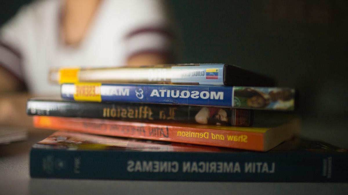 Stack of Spanish books on a table with student in the background 