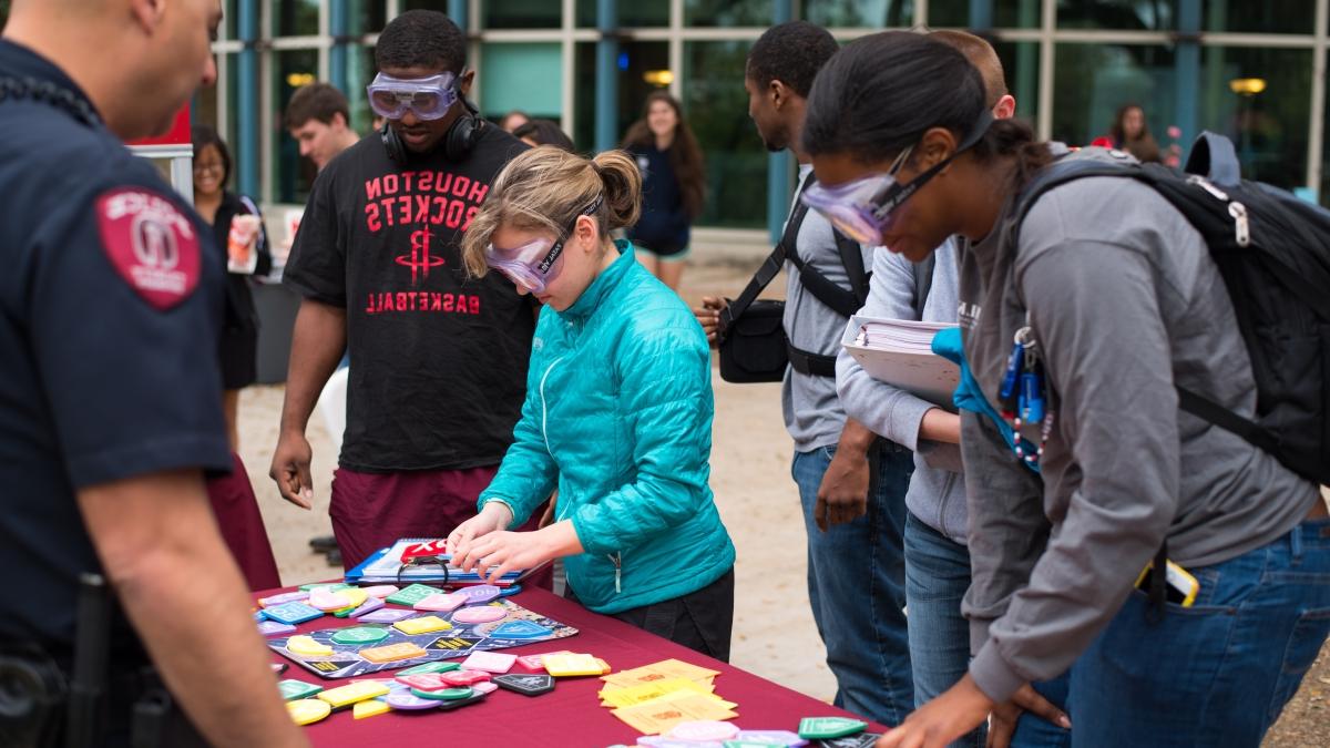 Group of students with goggles on finding things on a table at an Alcohol Awareness Spring Break event